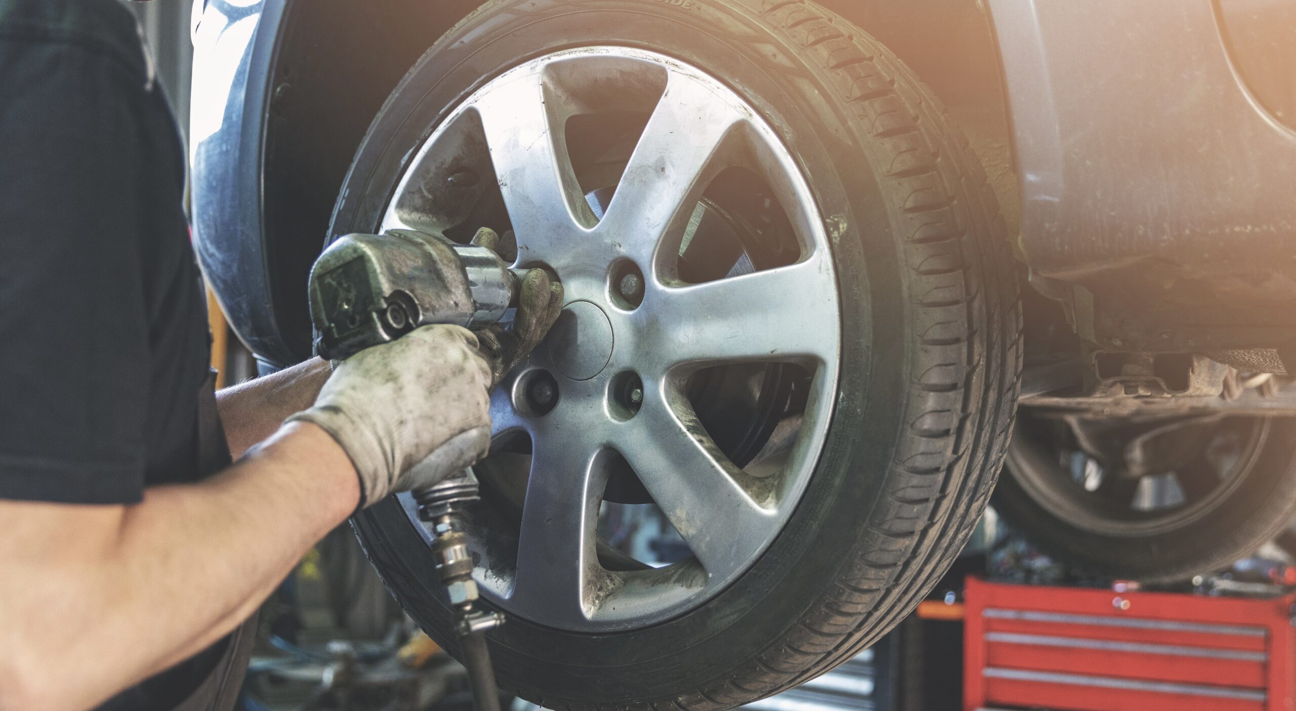 car mechanic screwing the wheel onto a vehicle at Telle Tire & Auto Centers during tire rotation.